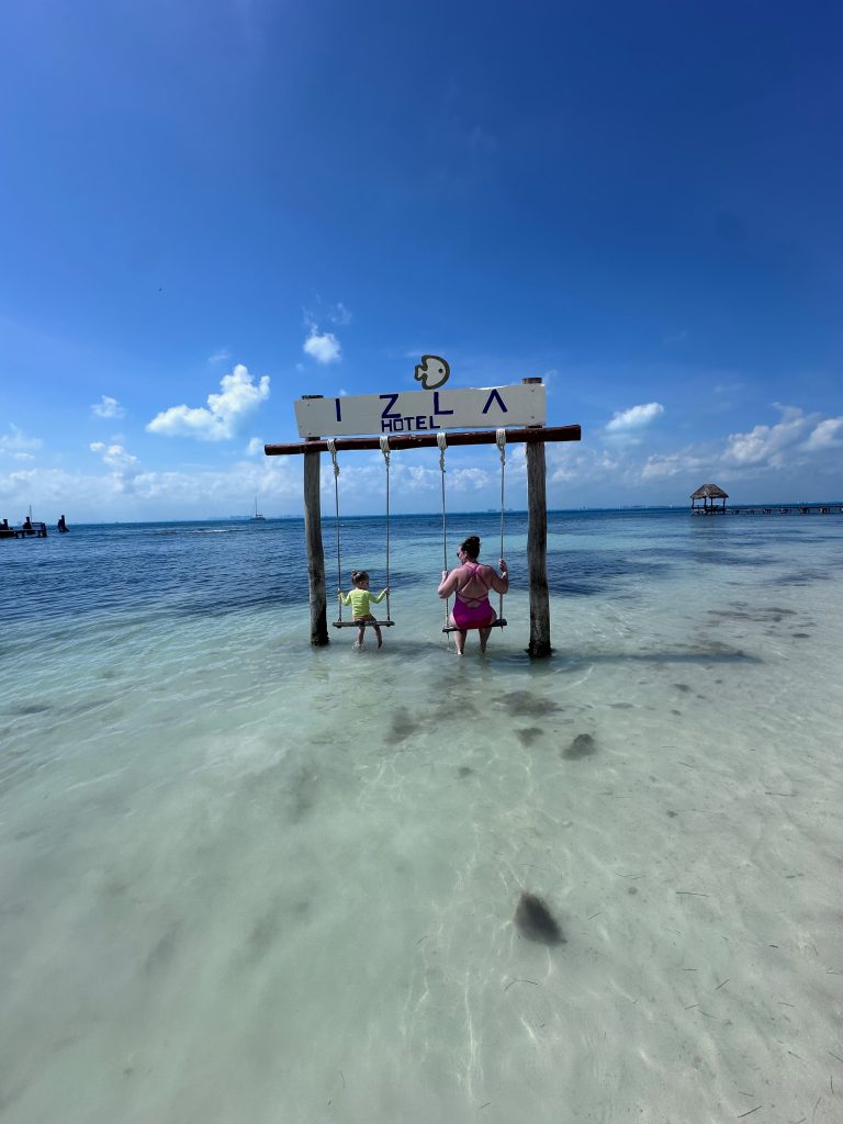 mom and daughter on swings in the ocean on Isla Mujeres